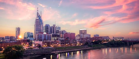 A city skyline with modern buildings, a river, and a bridge.