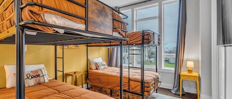 Una habitación con literas, una ventana con vistas y una pequeña mesa con una lámpara.