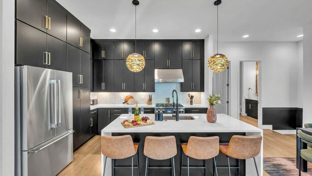 A modern kitchen with dark cabinetry, stainless steel appliances, and a central island with bar stools. - Rooftop Hot Tub City Views Pac-man Pool Table (Nashville)