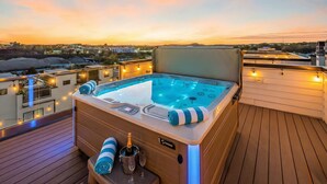 A hot tub on a deck with a sunset view, a champagne bottle, and glasses. - Rooftop Hot Tub City Views Pac-man Pool Table (Nashville)