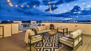 An outdoor deck with string lights, a sofa set, and a coffee table. - New Hot Tub Rooftop Decks City Views Poker (Nashville)