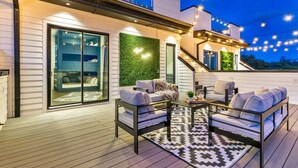 A modern outdoor patio with a sofa set, a coffee table, and string lights. - New Hot Tub Rooftop Decks City Views Poker (Nashville)