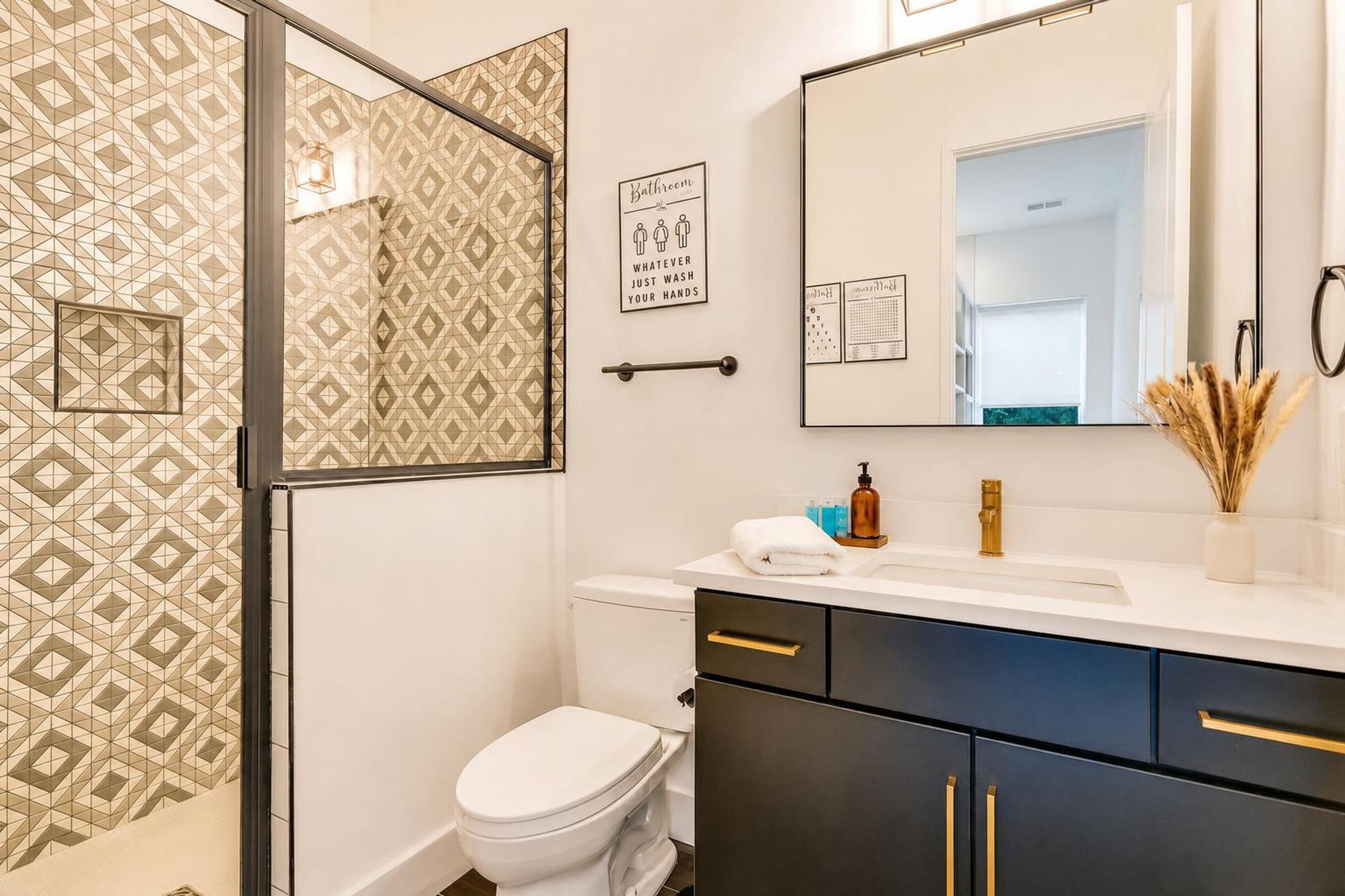Een badkamer met een behang, toilet, wastafel met spiegel en een handdoek.