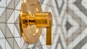 A wall-mounted, gold-colored, cylindrical object with a lever, set against a geometric patterned background. - New Hot Tub Rooftop Decks City Views Poker (Nashville)