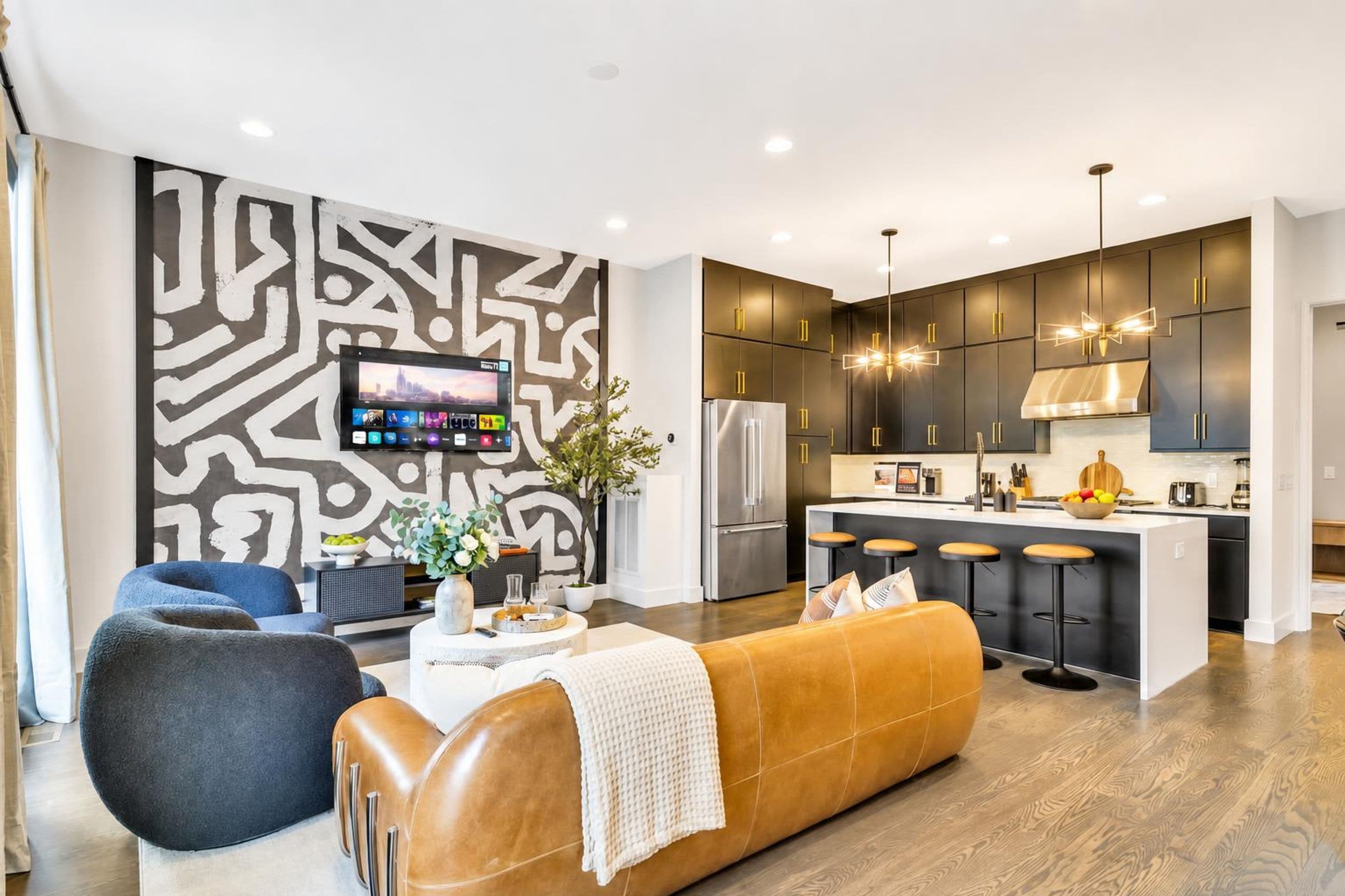 A modern kitchen with dark cabinets, stainless steel appliances, and a bar area with stools.