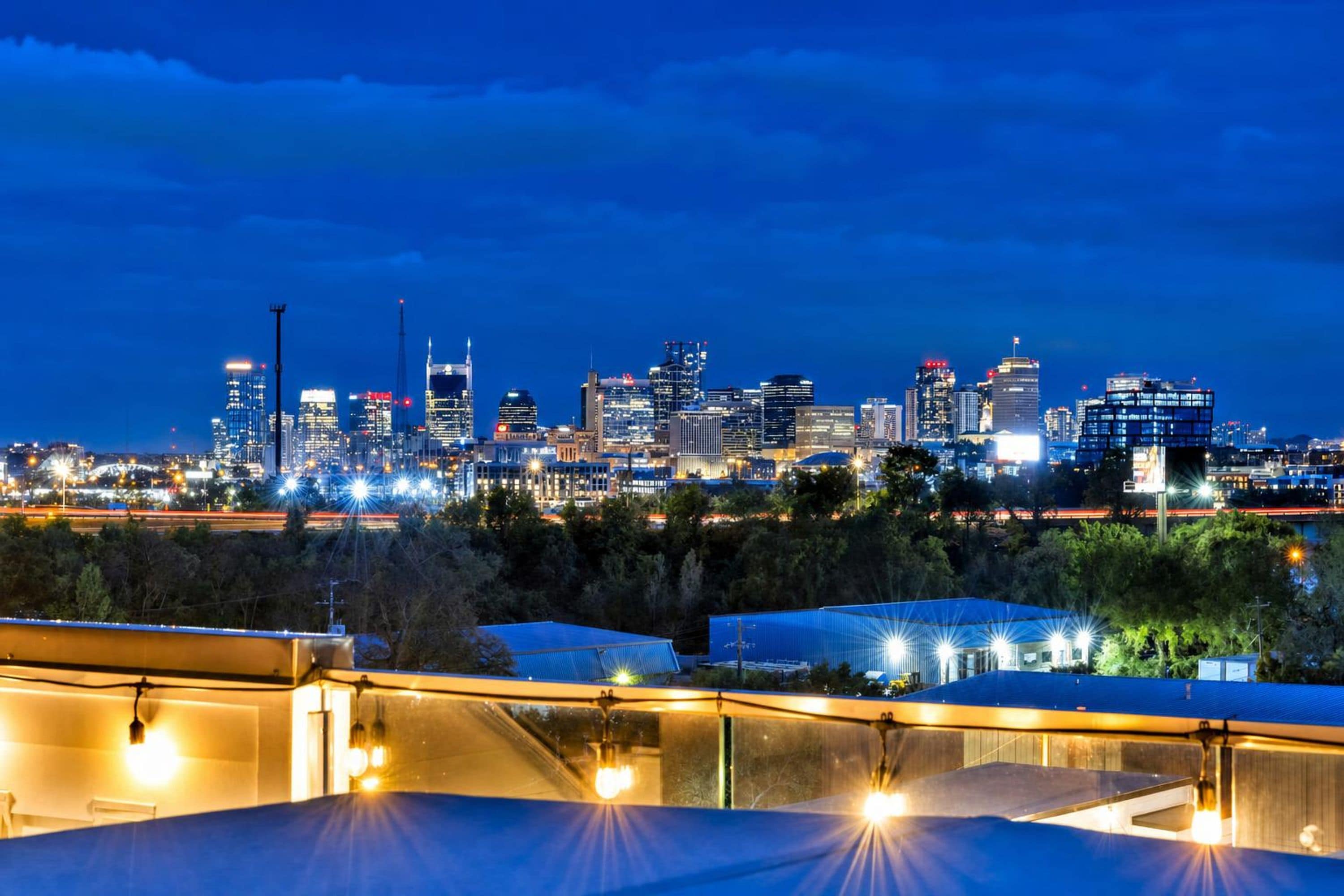 A city skyline at night with illuminated buildings and a clear sky.
