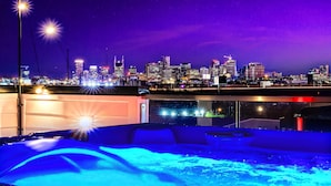 Nachtansicht einer Stadt mit einem Poolbereich, der eine Whirlwanne beinhaltet.