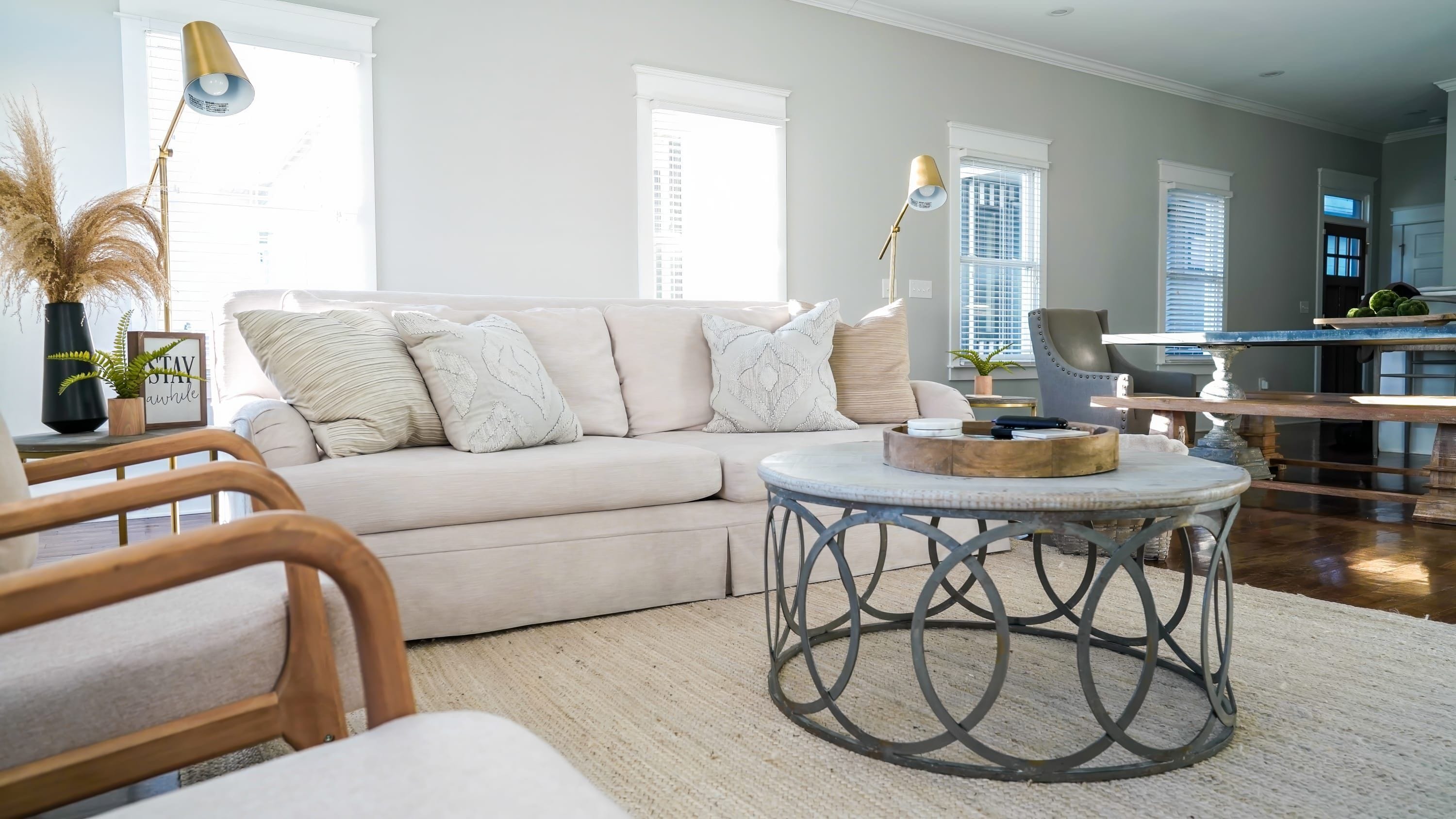 A living room with a beige sofa, round coffee table, and a wooden chair.