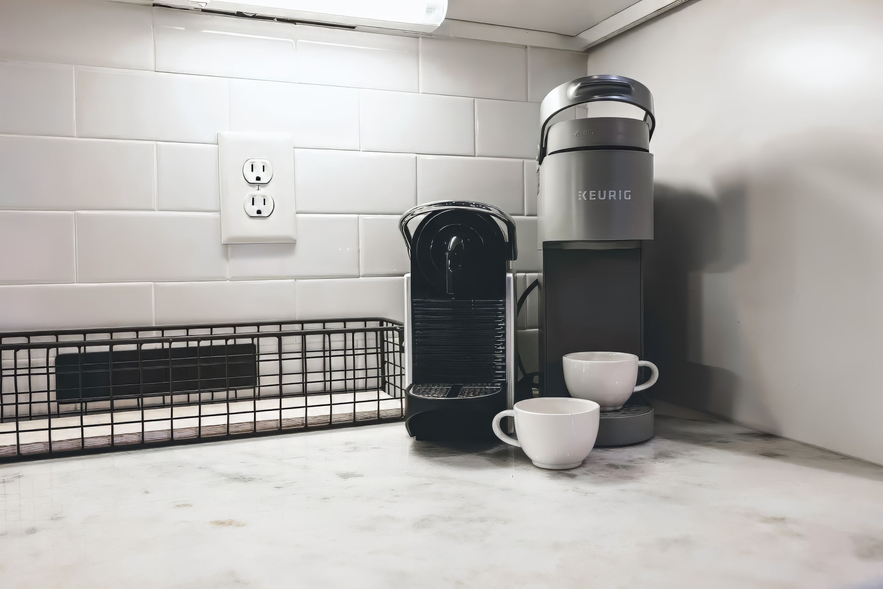 Eine Küche mit einer Kaffeemaschine, zwei Tassen und einem Wasserkocher auf einer Marmorarbeitsplatte.