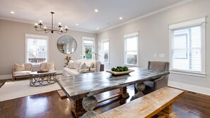 A spacious dining area with a large wooden table, benches, and a chandelier. - City Views Pool Hot Tub Mini Golf (Nashville)