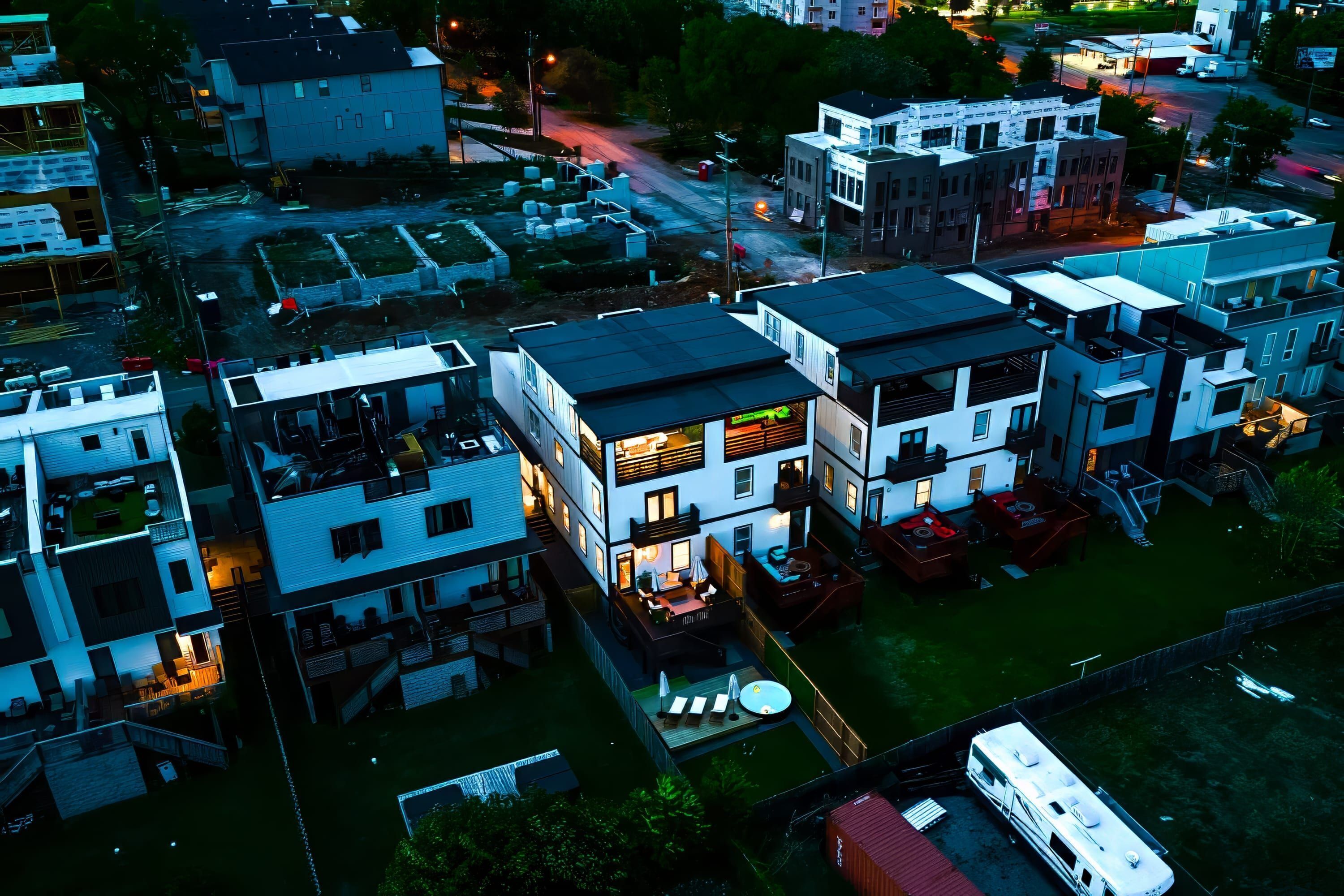 Un moderno complejo de apartamentos con varias unidades, piscina y un área exterior bien iluminada.