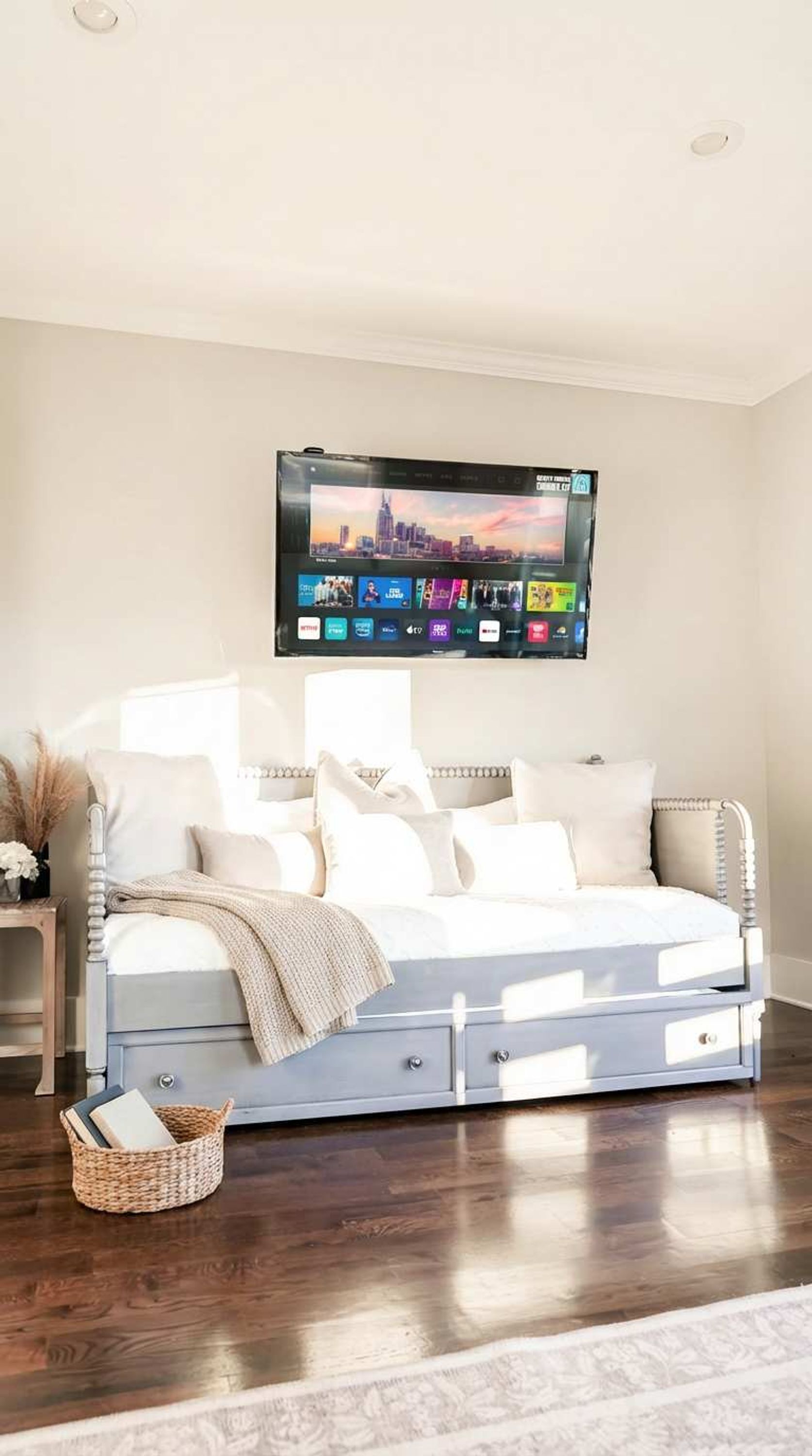 Une chambre à coucher avec un lit, un téléviseur fixé au mur et une table de chevet avec une lampe.
