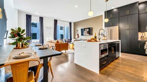 Une cuisine moderne avec des meubles noirs, un îlot central et un coin repas avec des chaises jaunes.