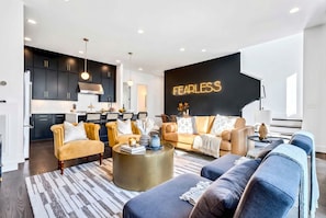 A modern living room with a sofa, coffee table, and a wall with the word 'FEARLESS' in neon lights. - Taylor Swift Themed Rooftops Hot Tub Views (Nashville)