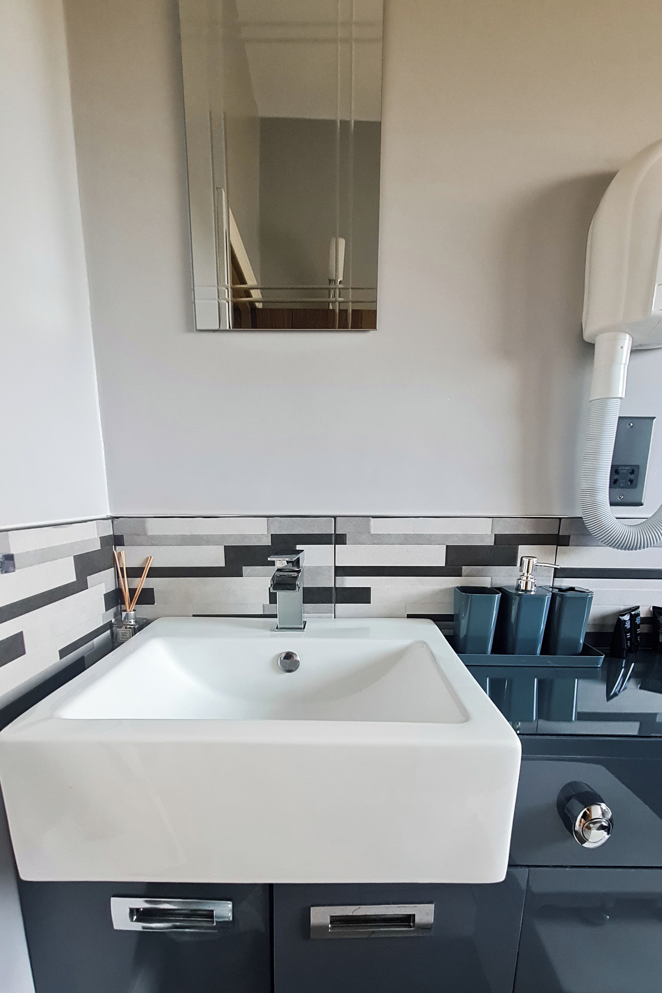 Une salle de bain moderne avec un lavabo blanc, un miroir et un porte-serviettes.