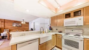 A modern kitchen with wooden cabinets, a white microwave, and a built-in oven. - Giant Steps #5 Ski / Ski out (Brian Head)