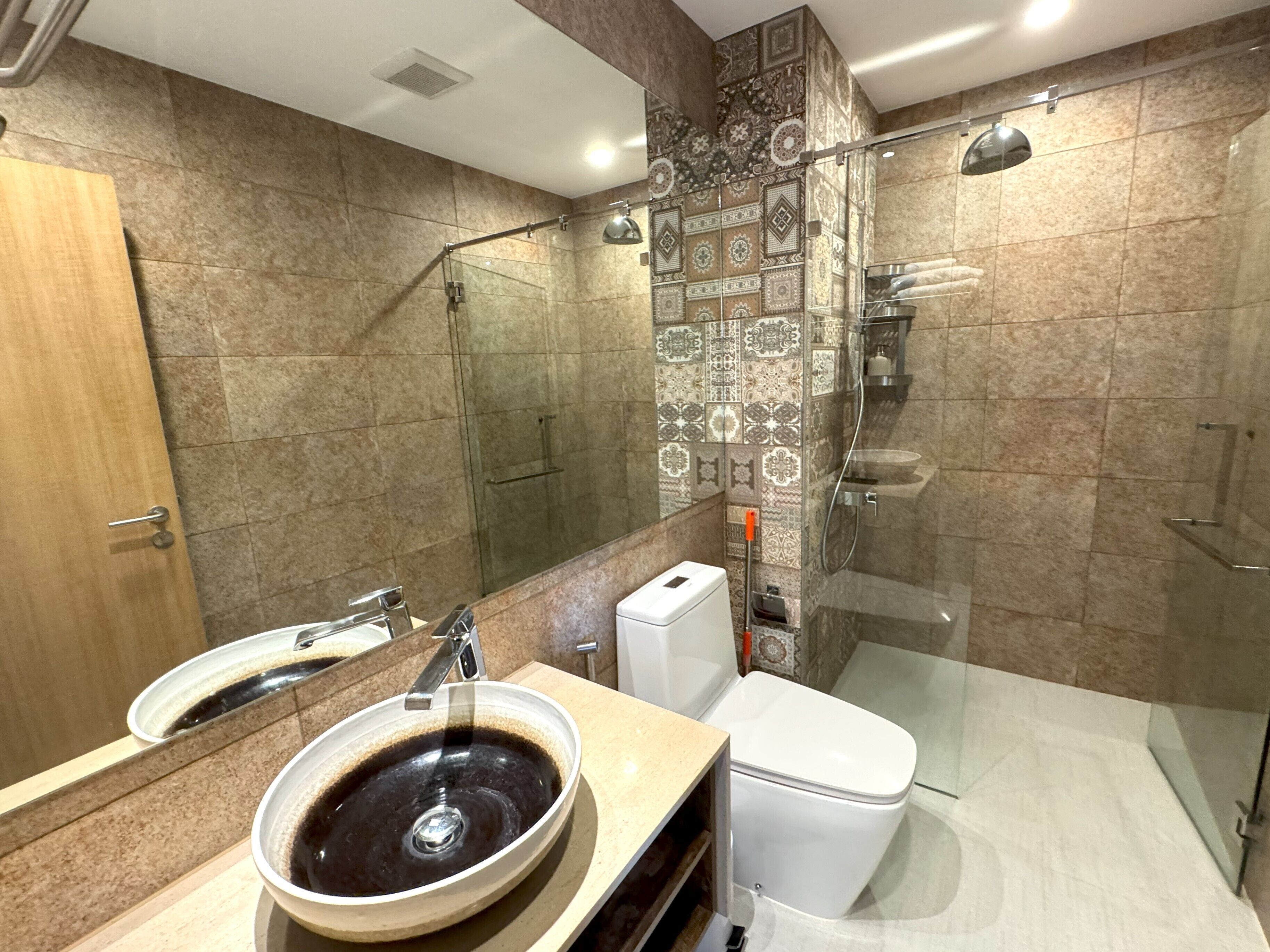 A modern bathroom with a glass shower enclosure, a sink with a bowl basin, and a toilet.