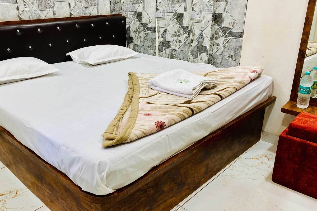 Un letto con struttura in legno, biancheria bianca e una coperta a motivi floreali.