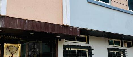 A two-story hotel with a signboard advertising AC and non-AC rooms.