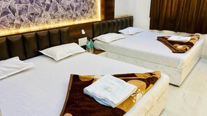 Habitación de hotel con dos camas, cada una con ropa blanca y almohadas, cabecero, pared con estampado de mármol y ventana con cortinas.