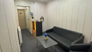 Ein kompakter Wohnraum mit einer Couch, einem kleinen Tisch und einer Heizung.