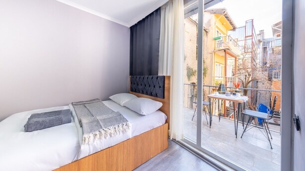 Ein Schlafzimmer mit Bett, Fenster und Blick auf einen Balkon.