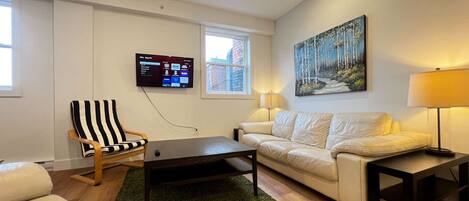 A living room with a TV, a sofa, a chair, a coffee table, and a painting on the wall.
