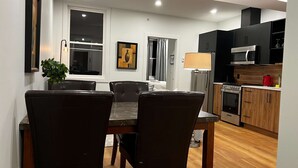 Una cocina moderna con microondas, horno y un hervidor rojo. Hay un comedor con mesa y sillas.