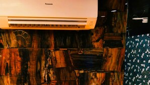 Een kamer met een houten wand, een witte airconditioning en een gele bank.