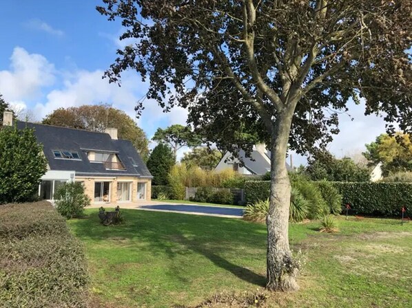 A house with a sloped roof, a front lawn, and a tree in the foreground. - Villa rental 15 persons direct access to the beach + heated swimming pool (Sarzeau)