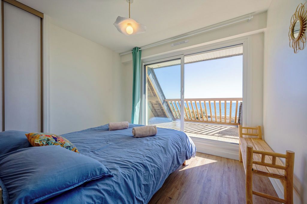 Une chambre à coucher avec un lit, un banc et un balcon offrant une vue.