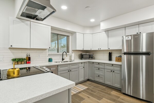 A modern kitchen with white cabinets, stainless steel appliances, and a central island.