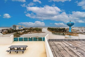 A view from a rooftop terrace overlooking a body of water, a dock, and a blue water tower.