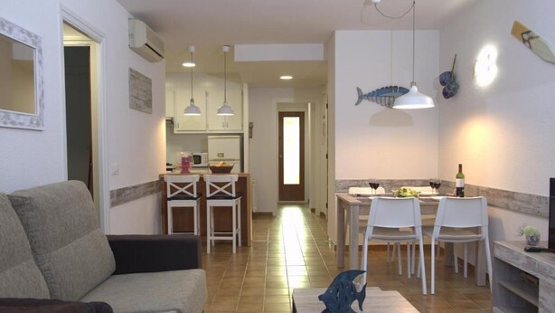 A living room with a sofa, a dining area with a table and chairs, and a kitchen in the background. - CHARMING APARTMENT (Sant Feliu de Guíxols)