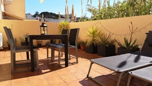 An outdoor patio with a table and chairs, potted plants, and a string of lights. - CHARMING APARTMENT (Sant Feliu de Guíxols)