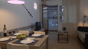A dining area with a table set for four, a television, and a balcony with a view. - CHARMING APARTMENT (Sant Feliu de Guíxols)