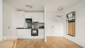 Eine moderne Küche mit weißen Schränken, einem schwarzen Backofen und einem Holztisch.