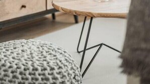Ein modernes Wohnzimmer mit einem Flachbildfernseher, einem Holztisch und einem gestrickten Pouf.