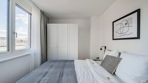 Un dormitorio con cama, armario, ventana y una obra de arte enmarcada en la pared.