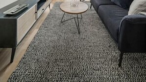 Una sala de estar moderna con un sofá, una mesa de centro, un televisor montado en la pared y un balcón con una mesa y sillas.