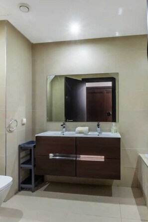 Un baño con lavamanos doble, espejo y inodoro.