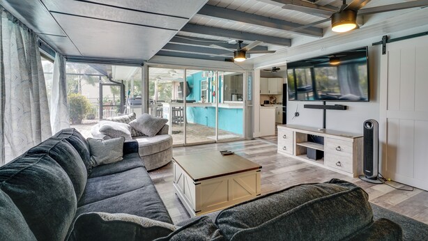 A modern living room with a grey sofa, a coffee table, and a TV mounted on the wall. - < 1 Mi to Four Freedoms Beach: Canal-front Getaway (Cape Coral)