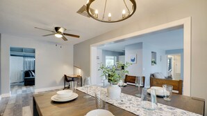 A dining area with a wooden table set for four, a ceiling fan, and a chandelier. - < 1 Mi to Four Freedoms Beach: Canal-front Getaway (Cape Coral)