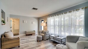 A modern living room with a sofa, armchair, ottoman, and a coffee table. - < 1 Mi to Four Freedoms Beach: Canal-front Getaway (Cape Coral)