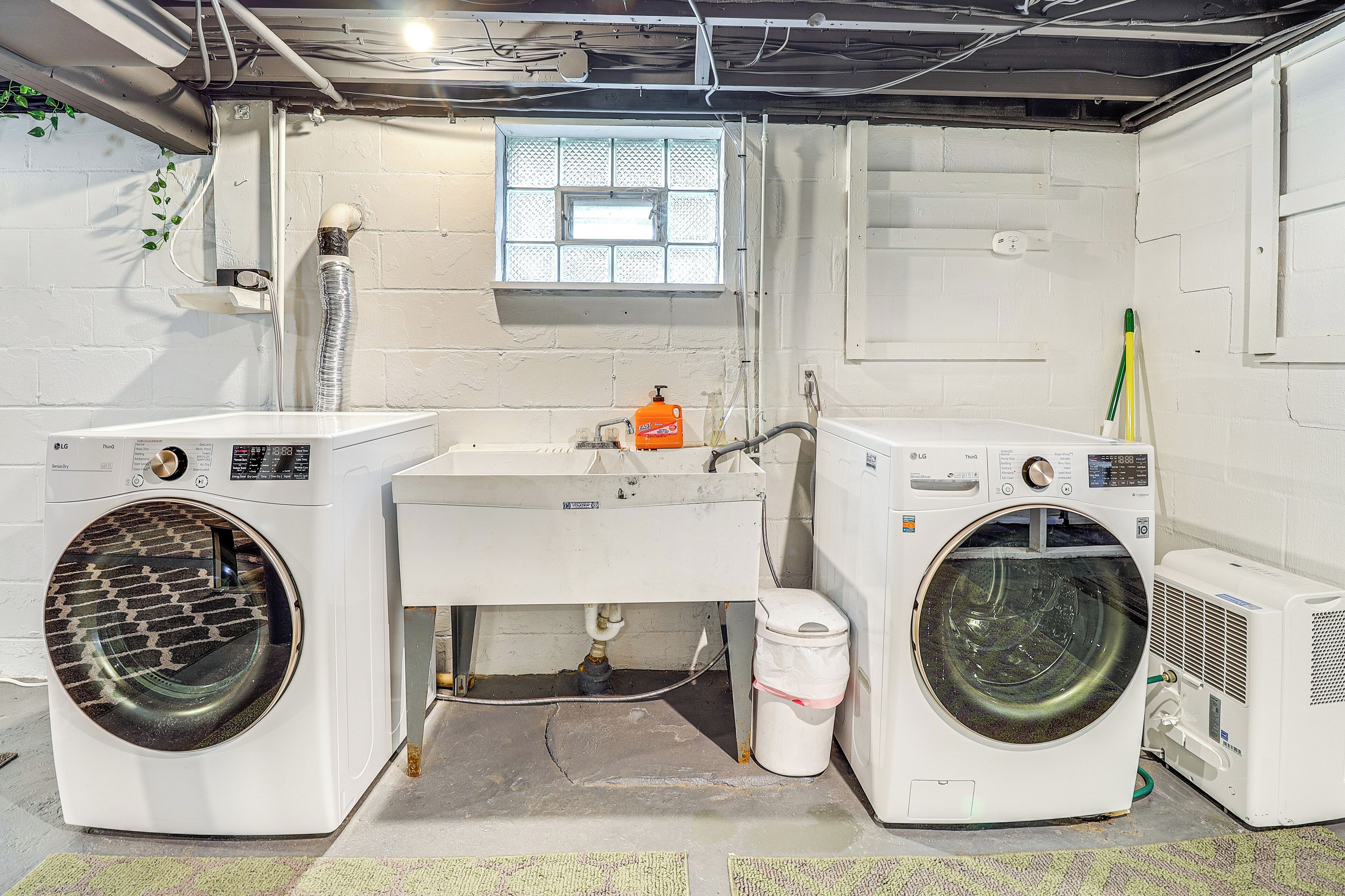 A laundry room with two washing machines, a sink, and a window.