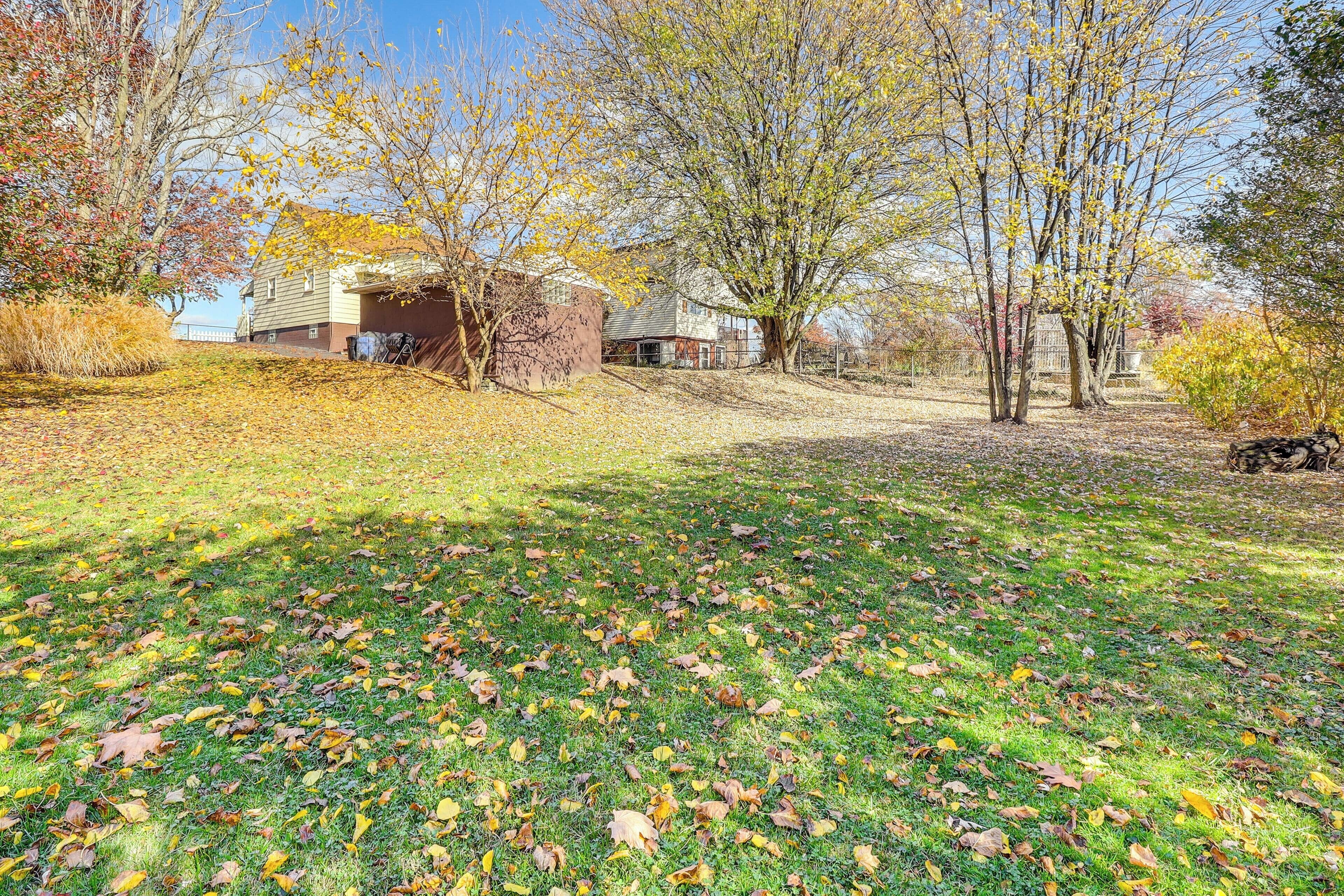 A residential area with houses, a grassy lawn, and trees with autumn leaves.