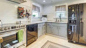 A modern kitchen with stainless steel appliances, white cabinetry, and a tiled backsplash. - Game Room & Fire Pit: West Mifflin Home! (West Mifflin)