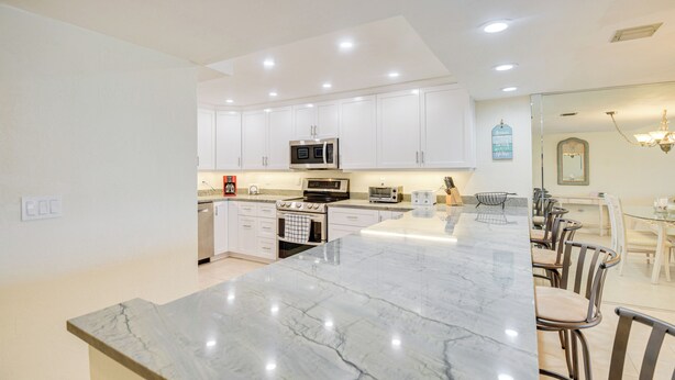 A modern kitchen with white cabinets, a marble countertop, and built-in appliances.