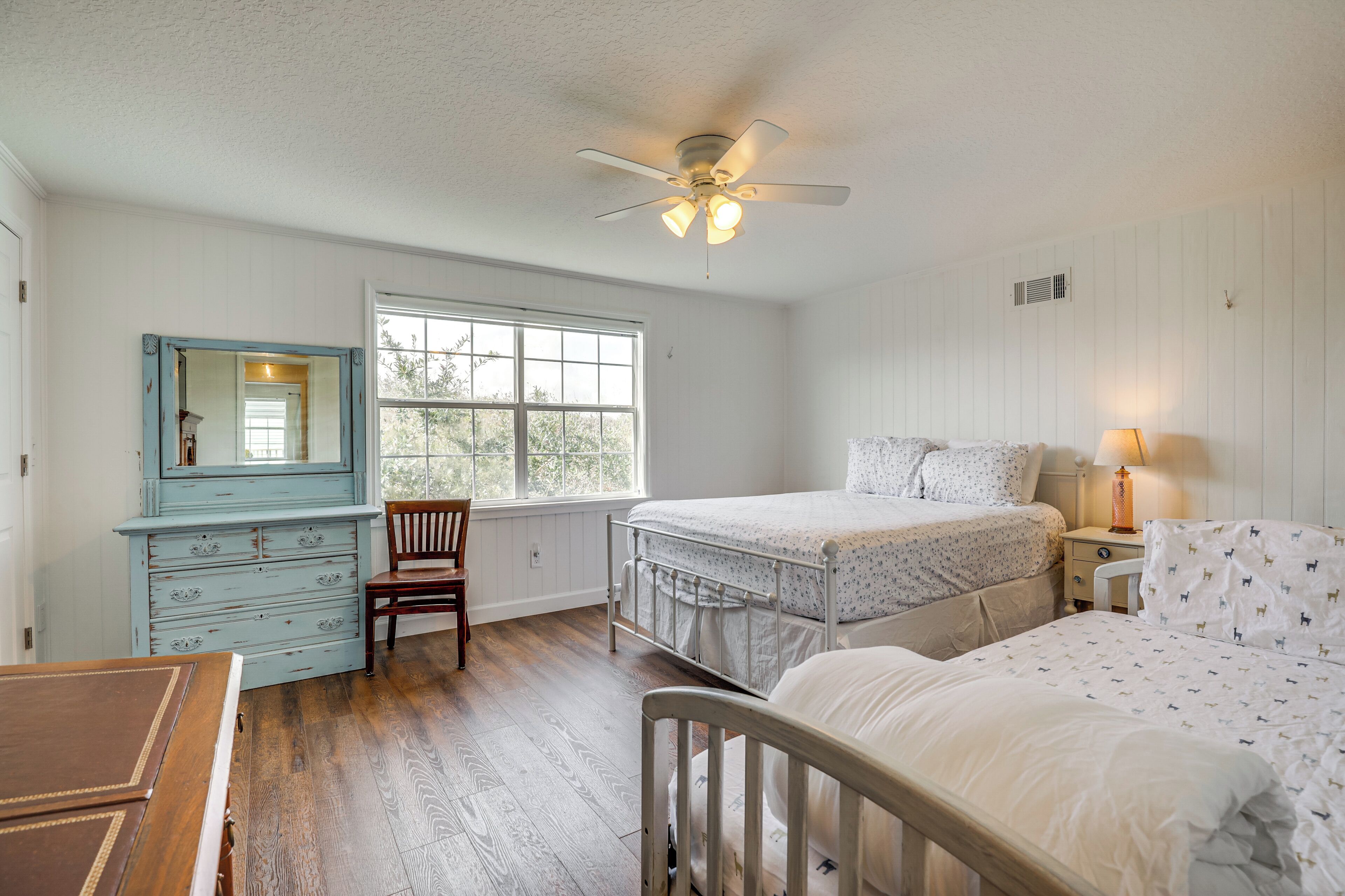 A bedroom with a bed, a nightstand, a dresser, a chair, and a window.
