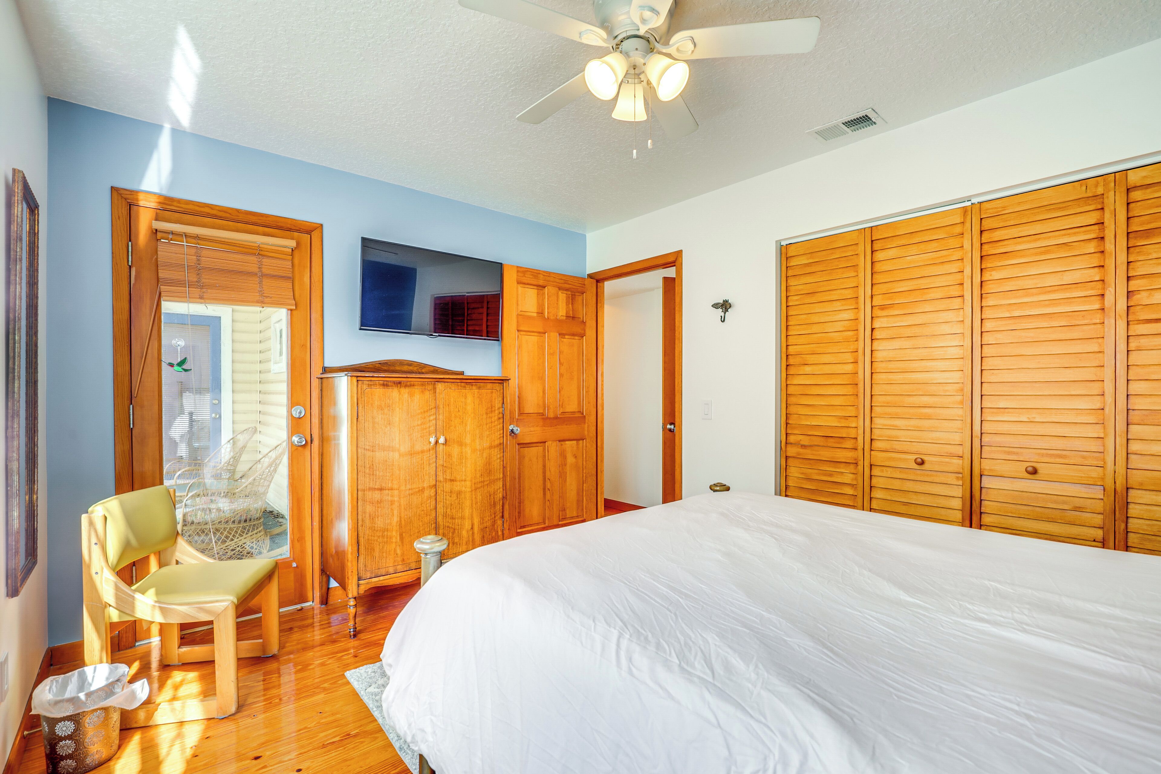 A bedroom with a large bed, wooden wardrobe, and a ceiling fan.